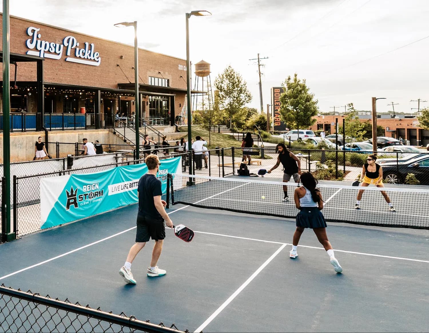 A doubles pickleball game on the courts outside Tipsy Pickle